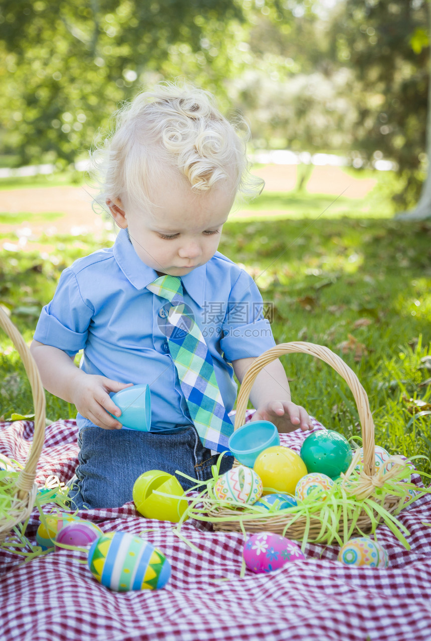小男孩在公园野餐的毯子上玩彩色蛋壳图片