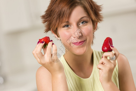 漂亮的红发女人在厨房里吃草莓图片