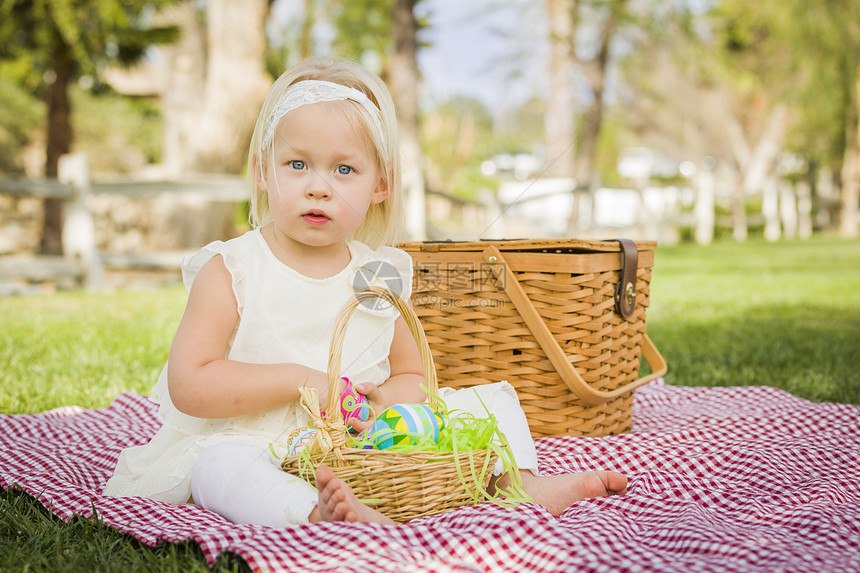 小女孩在公园野餐的毯子上玩彩色蛋壳图片