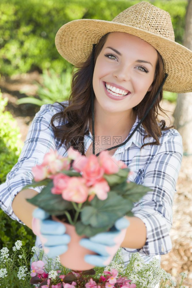 身着帽子和手套露天园艺的年轻快乐成女子图片