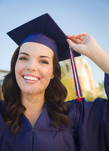 快乐毕业的混血女子穿着帽和礼服在校园庆祝令人愉快的高清图片素材