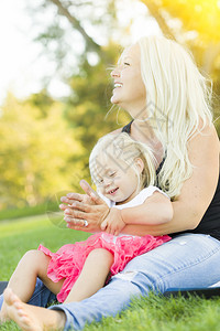美丽的母亲和小女孩在草地上玩得开心图片