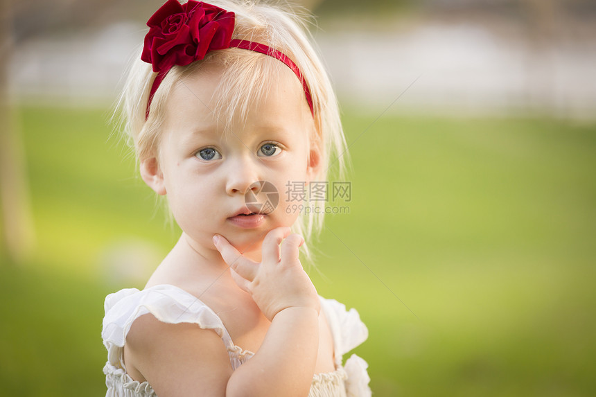 美丽的可爱小女孩手放在脸上穿着白色衣服在草地上图片