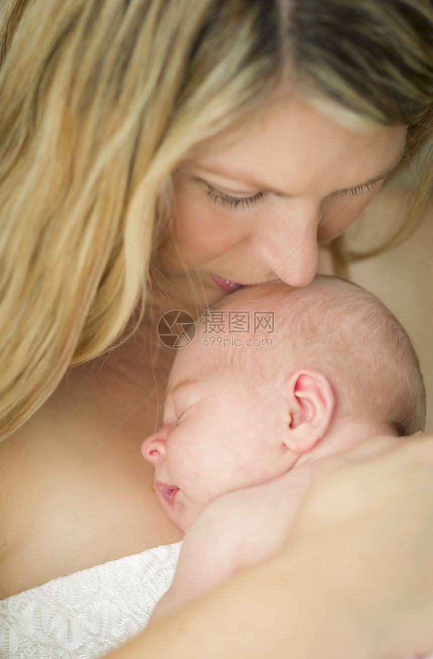 年轻的天主教青美丽的母亲抱着她珍贵的新生女婴图片