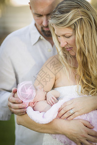 美丽的年轻夫妇抱着他们新生的女婴在外面父亲高清图片素材