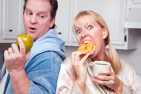 吃甜甜圈夫妻在厨房吃甜圈咖啡或健康水果背景