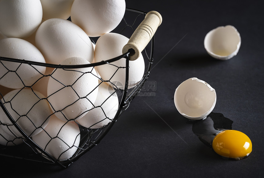 在黑木桌上的金属篮子中鸡蛋与黄和碎壳直接放在桌上的碎蛋谚语概念图像don将所有鸡蛋放入一个篮子图片
