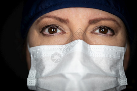 女医生或护士在黑暗背景中戴着医疗面罩图片