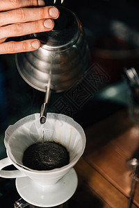 将沸水从壶倒到陶瓷滴灌咖啡机的垂直图像关闭图片
