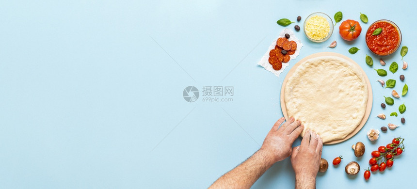 一步地做比萨饼男人和双手伸展在比萨石头上的面团披萨成分直接放在桌子上图片