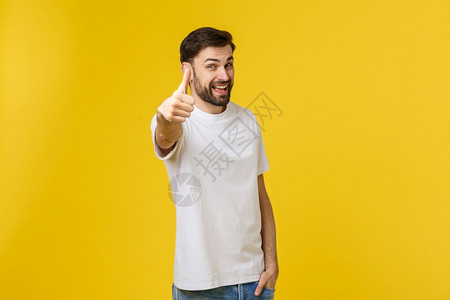 年轻快乐的男子在黄色背景的散居者中挂起拇指标志工作室高清图片素材