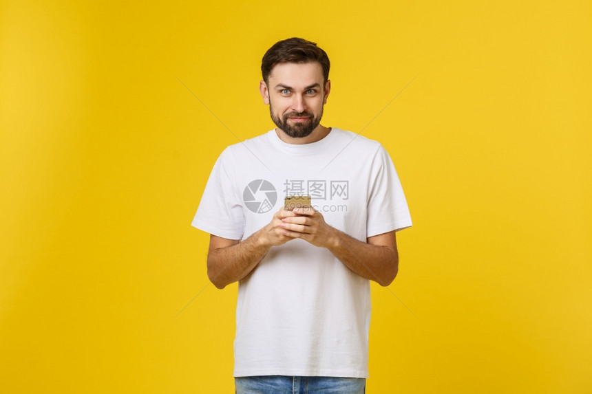 一位在电话上交谈的严肃男子肖像他用黄色背景孤立在电话上看着相机一个严肃的人在电话上交谈的严肃男子肖像他用黄色背景孤立在手机上图片