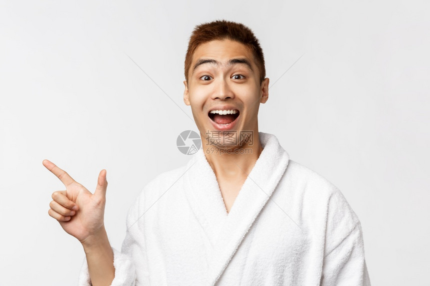 美丽spa和休闲的概念兴奋快乐在浴袍中的亚洲人笑向左指展示广告推荐好地方以放松美spa和休闲的概念兴奋愉快向左指广告建议好地方以图片