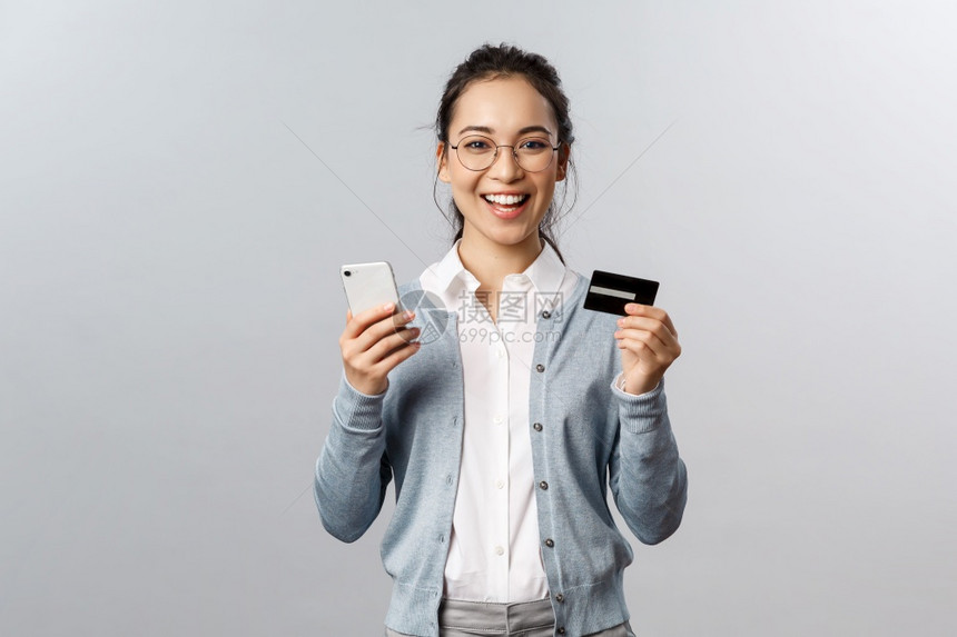 带着眼镜的女孩手上拿着手机和银行卡图片