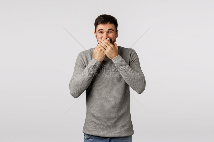 穿着灰色毛衣的可爱成人男子按手对嘴唇和笑尽量不制造噪音办公室的同事说闲话男人不能在严肃的会议中笑躲在嘴后男人不能在严肃的会议上笑图片