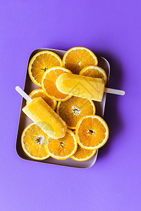 橙色冰淇淋和橘子片放在盘里紫色背景的顶美味自制橙子冰淇淋图片