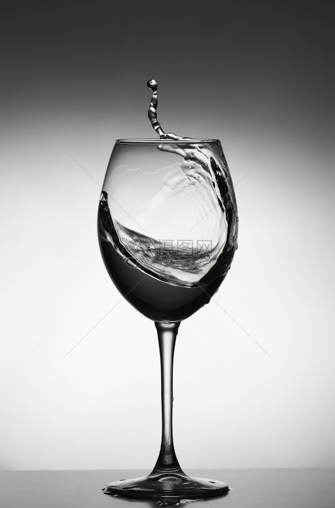 白葡萄酒喷洒在灰色背景玻璃的轮廓选择焦点图片