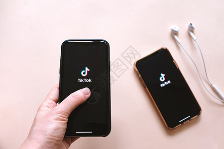 持手机ChangkoThailndThgkoThailndpril290两台智能手机和持iphone平铺x在屏幕上用耳机显示Tikto背景