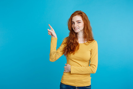 年轻漂亮的红头发女孩对某事很满意手指尖蓝色糊面背景复制空间背景