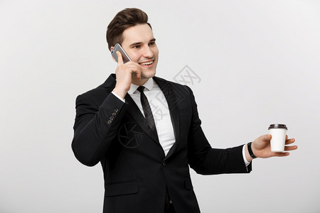 商业概念有自信的年轻英俊商人在手机上交谈白色孤立的背景下喝咖啡男性的高清图片素材