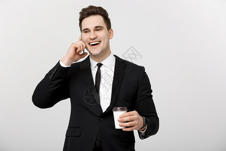 商业概念有自信的年轻英俊商人在手机上交谈白色孤立的背景下喝咖啡细胞高清图片素材