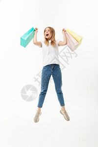 一个快乐的漂亮女孩拿着购物袋跳看镜头孤立在白色背景上一个快乐的漂亮女孩拿着购物袋跳看镜头销售高清图片素材