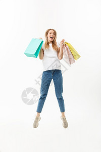 一个快乐的漂亮女孩拿着购物袋跳看镜头孤立在白色背景上一个快乐的漂亮女孩拿着购物袋跳看镜头举办高清图片素材