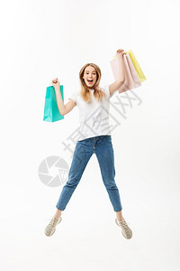 一个快乐的漂亮女孩拿着购物袋跳看镜头孤立在白色背景上一个快乐的漂亮女孩拿着购物袋跳看镜头买方高清图片素材