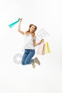 一个快乐的漂亮女孩拿着购物袋跳看镜头孤立在白色背景上一个快乐的漂亮女孩拿着购物袋跳看镜头令人愉快的高清图片素材