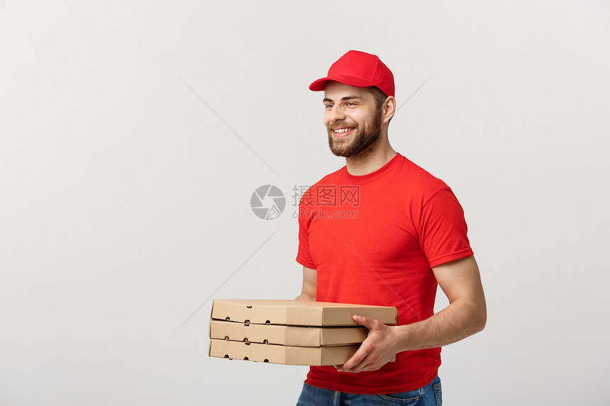 交付概念年轻的causin英俊的送披萨员拿着盒与灰色背景隔绝英俊的比萨递员与灰色背景隔绝的披萨盒图片