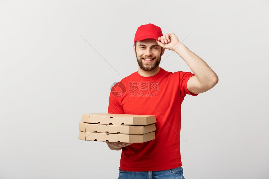 交付概念年轻的causin英俊的送披萨员拿着盒与灰色背景隔绝英俊的比萨递员与灰色背景隔绝的披萨盒图片