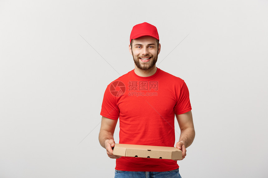 快乐的年轻送货员拿着比萨饼盒却与白人工作室背景隔绝图片