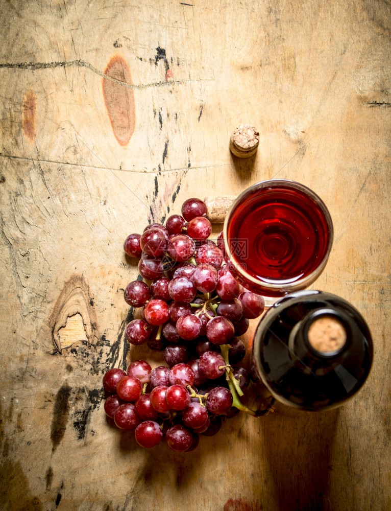 红葡萄和一瓶酒木制背景图片