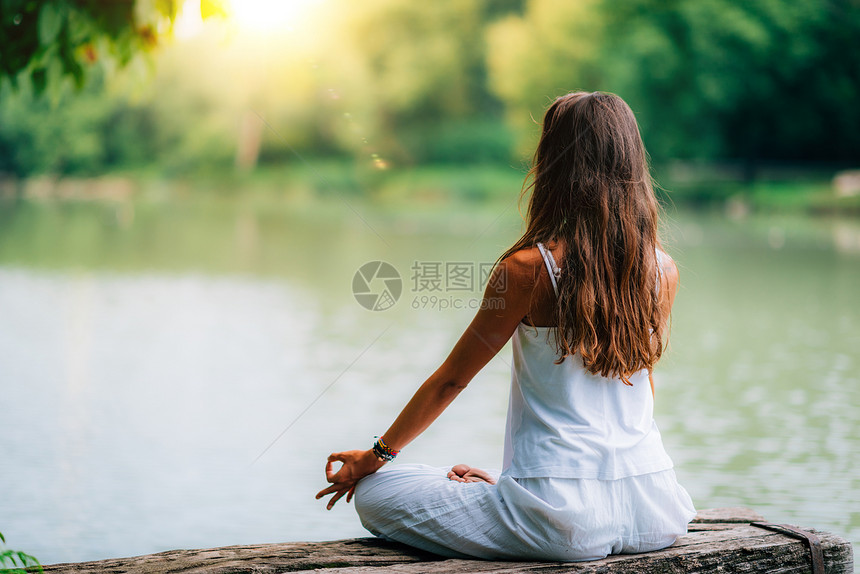 女人在湖边做瑜伽坐在莲花的姿势和手指放在泥巴位置图片