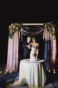 新娘和郎正在切他们的结婚蛋糕漂亮的灯光婚礼概念图片