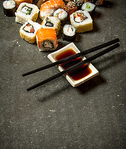 卷子和寿司加酱油在石板上图片