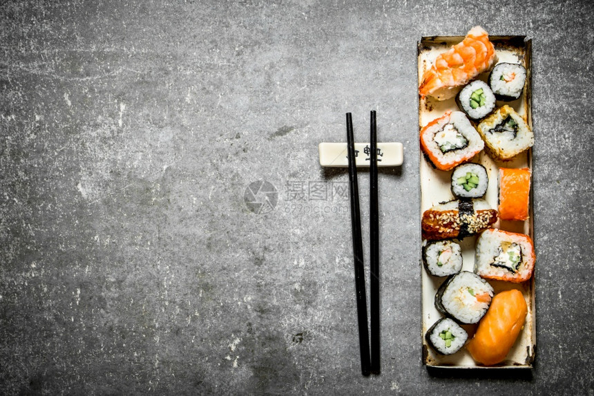 一张寿司卷和海鲜放在石板上图片
