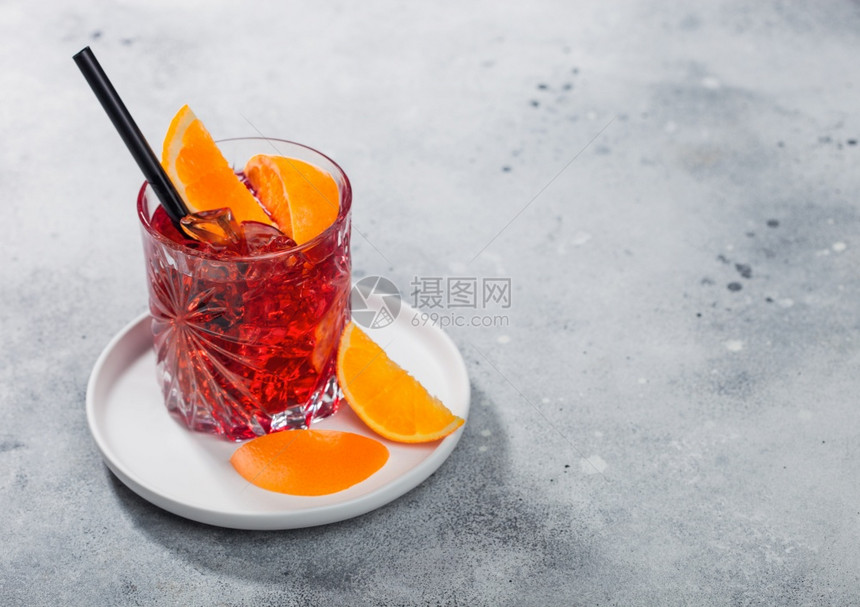 白陶瓷板的晶玻璃中白葡萄鸡尾酒在光桌背景上有橙片和黑稻图片