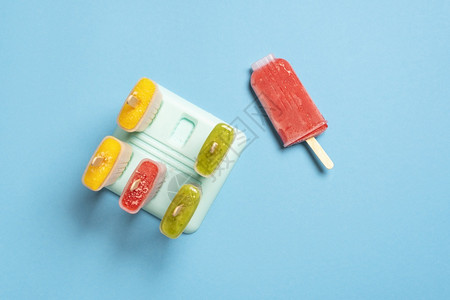 冰棒模具蓝色桌子上冰淇淋的在的模子上顶端风景家里做的冰淇淋新鲜水果配素食成分的夏季甜点背景