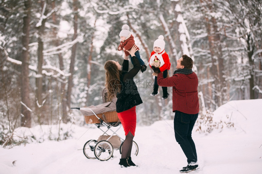 一对夫妇怀抱孩子在雪地与婴儿车合影图片