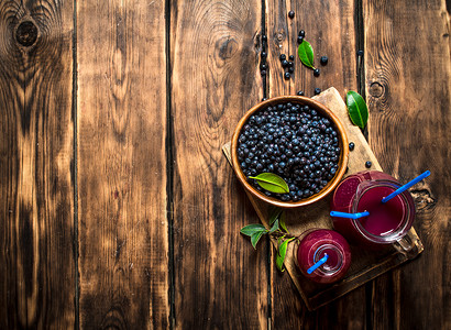 蓝莓新鲜果汁放在木制桌子上蓝莓汁放在木制桌子上饮酒高清图片素材