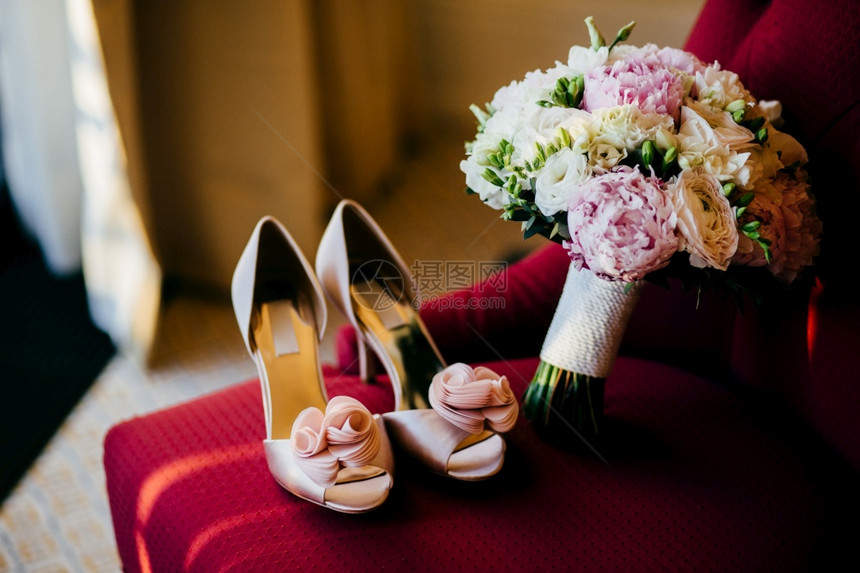 红椅子上的鲜花婚礼准备配件粉红新娘的鞋子和房间的红花束图片