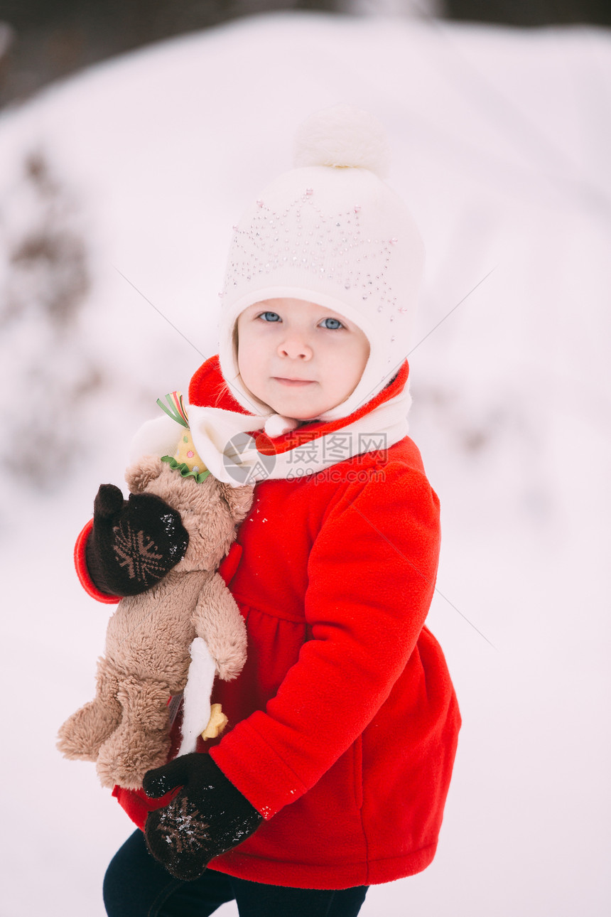穿着红大衣的小女孩和一只泰迪熊在冬天玩得开心女孩在雪地玩耍女孩在冬天玩得开心图片