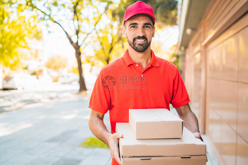 一个送货员的肖像和纸板披萨盒在街上户外送货和运输服务的概念图片