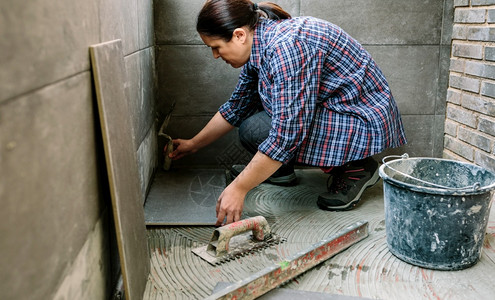 女手工人在露台铺设新的瓷地板图片