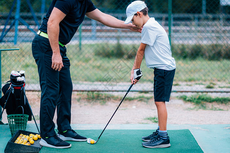 高尔夫课教官给一个小男孩上游戏课背景图片