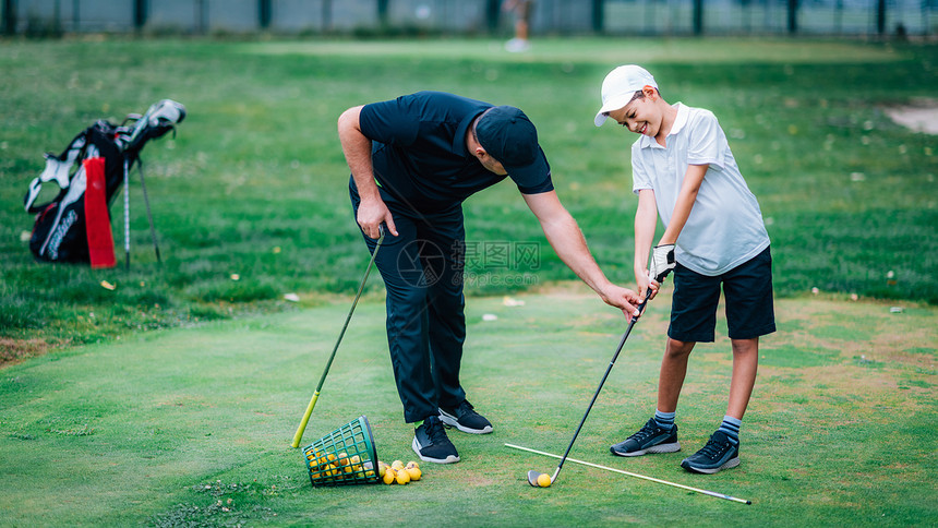 一个高尔夫教练和一个男孩在练习高尔夫图片