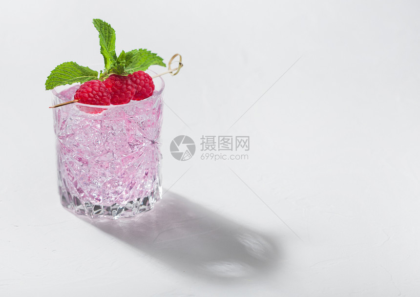 清凉的夏季粉红柠檬鸡尾酒在水晶玻璃中白底带有草莓冰和薄荷图片