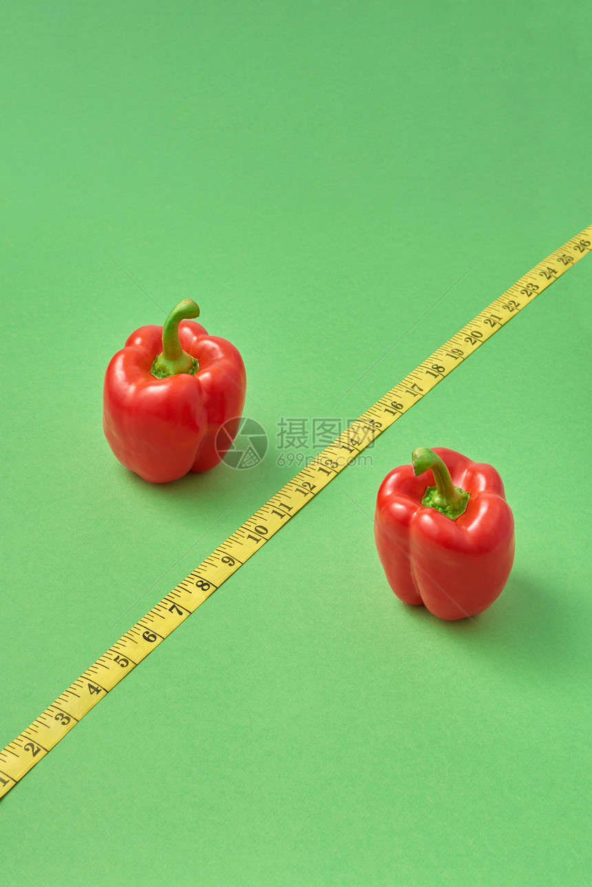 由两种红辣椒和对角黄测量带组成的健康在绿色背景上表示百分之复制空间低卡路里食物以减肥红有机辣椒和测量带的百分之符号图片