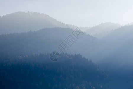 来自模糊的雾山美丽宁静风景树木在库夫斯坦奥特里亚阳光明媚的天空下图片